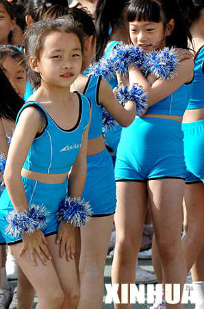 5月9日，参加表演的孩子们在风中等待讲话结束。