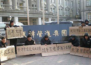 图片：农民工们举着“过年了老婆孩子在等钱”“还我血汗钱”等标语在天津管道集团门前 ...