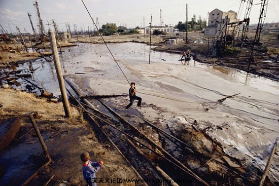 儿童在油泵泄漏形成的漆黑的油池中玩耍，1993年摄于阿塞拜疆的巴拉夏尼（Balaxani） ...